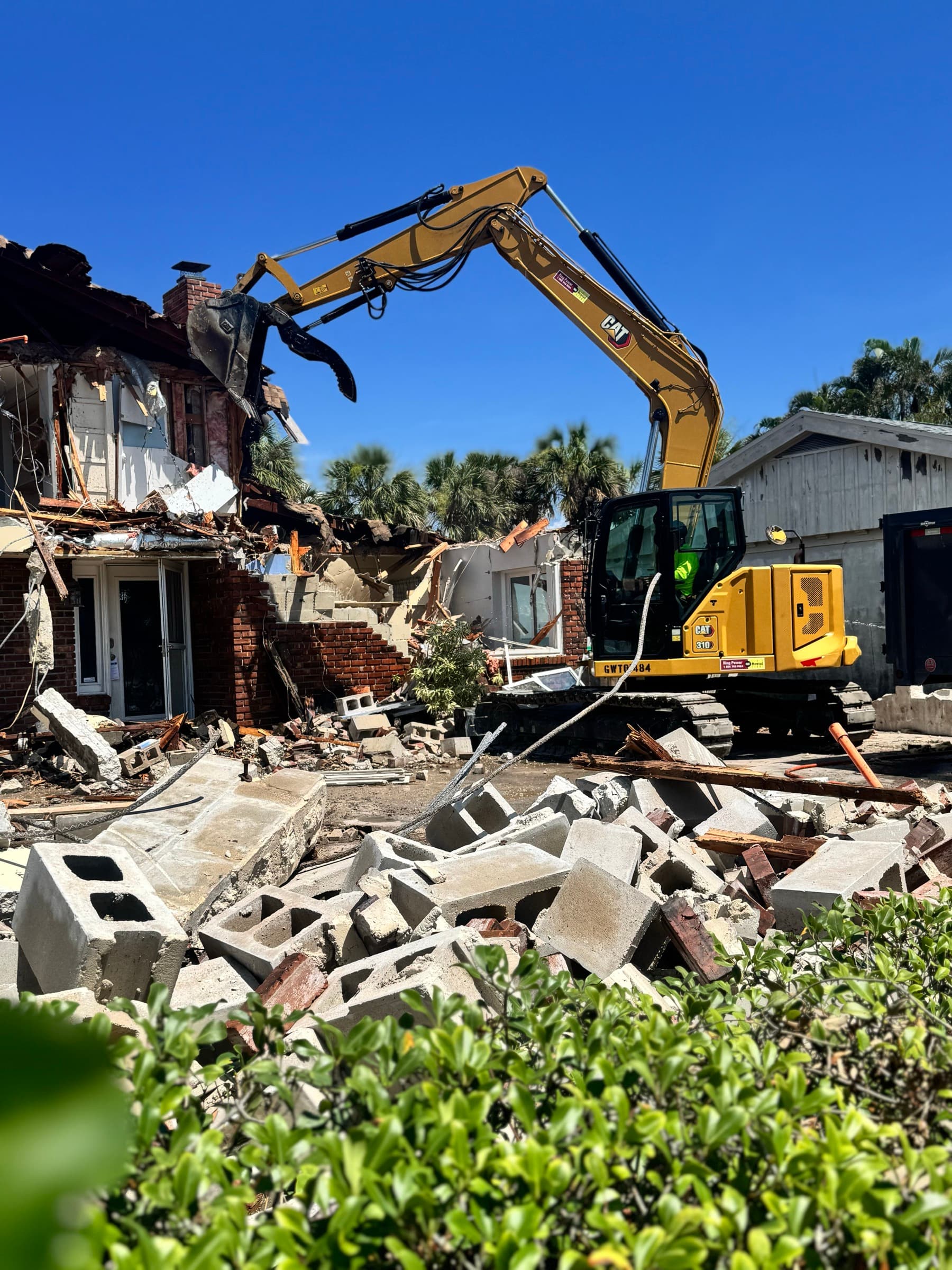 Excavator removing demolition debris from a residential structure