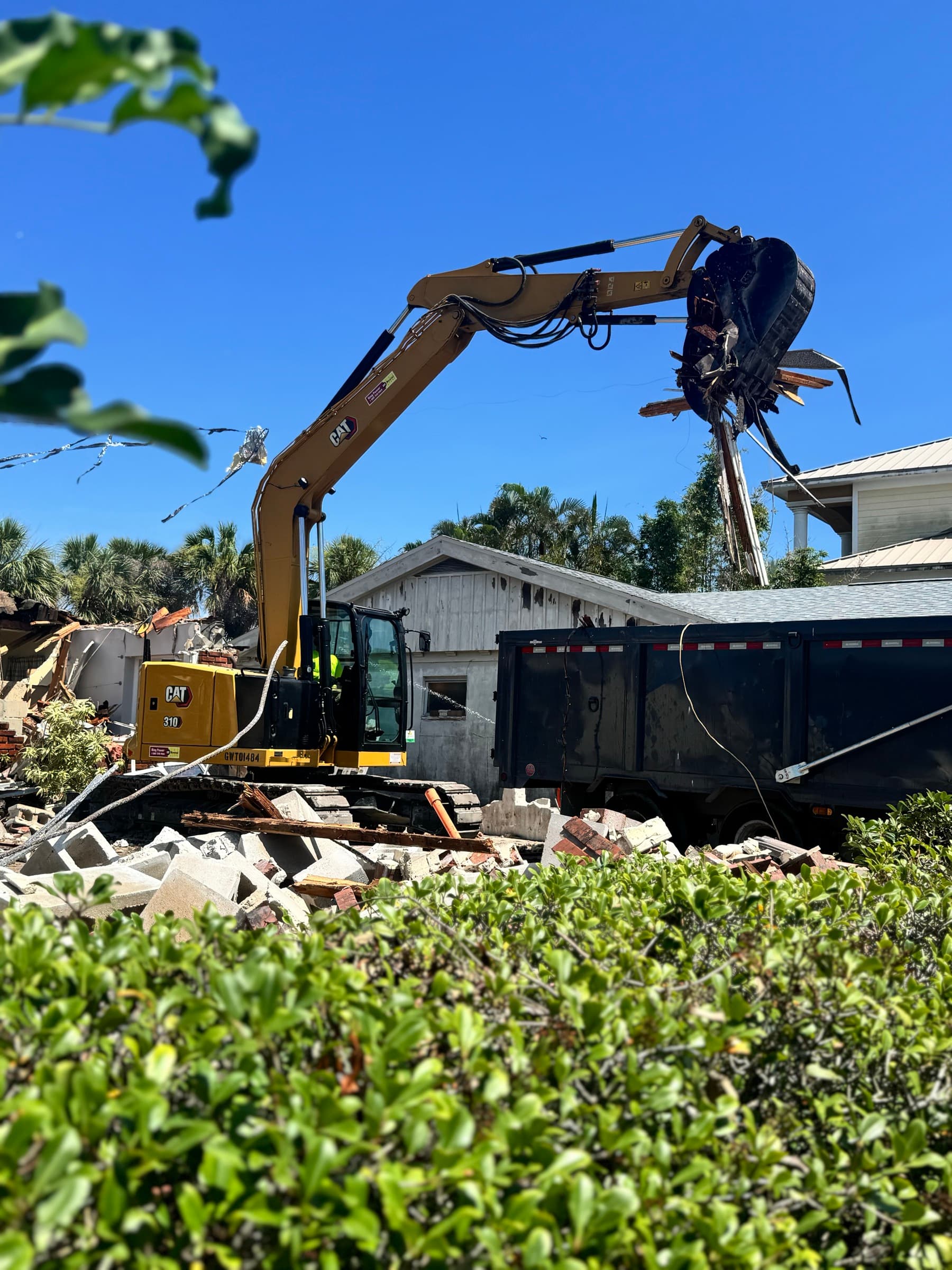 Excavator loading demolition debris into a dump trailer